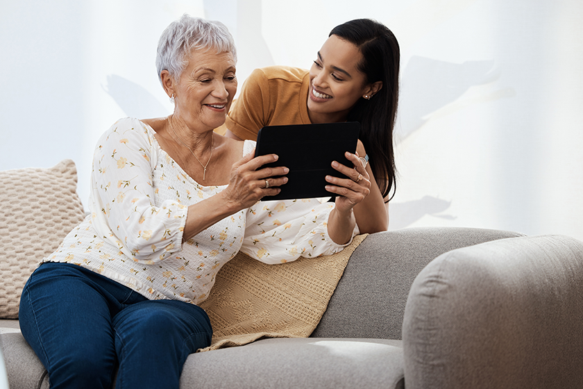 how do you download an app. a senior woman using a digital tablet with her daughter on the sofa at home